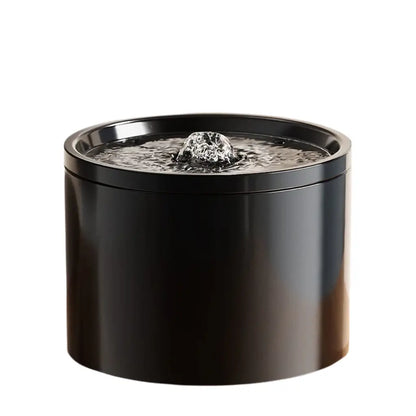 Black cylindrical ceramic water fountain with bubbling water on a white background