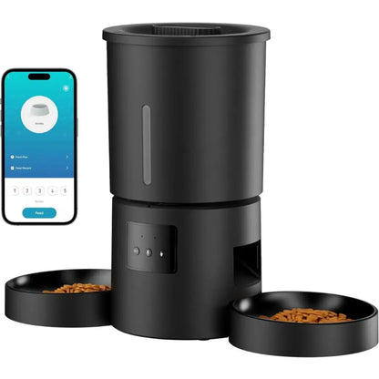 Black pet feeder with two bowls of food and a smartphone displaying an app interface