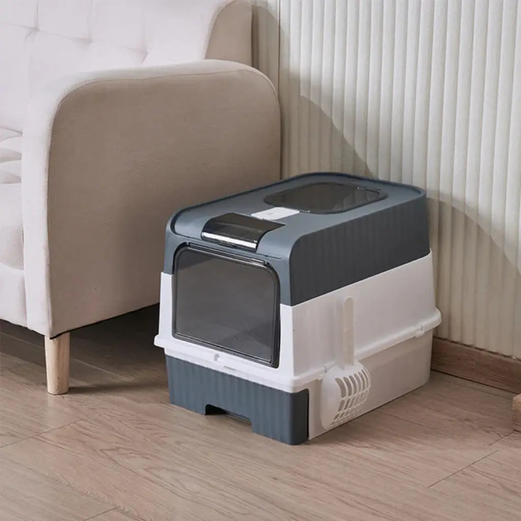 Cat litter box on a wooden floor next to a beige sofa