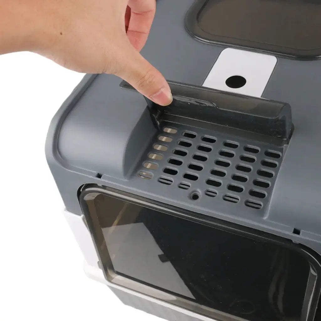 Hand opening a gray litter box with a transparent window
